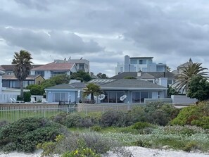 Un quartier résidentiel avec des maisons, une cour clôturée et une plage en arrière-plan.