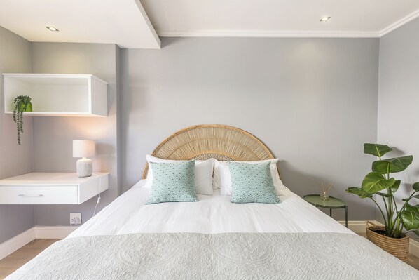 A modern bedroom with a bed, bedside table, and a wall-mounted shelf. - Beachfront, Private Pool, Pizza Oven, Pool Table, Fast Internet, Family Friendly (Cape Town)