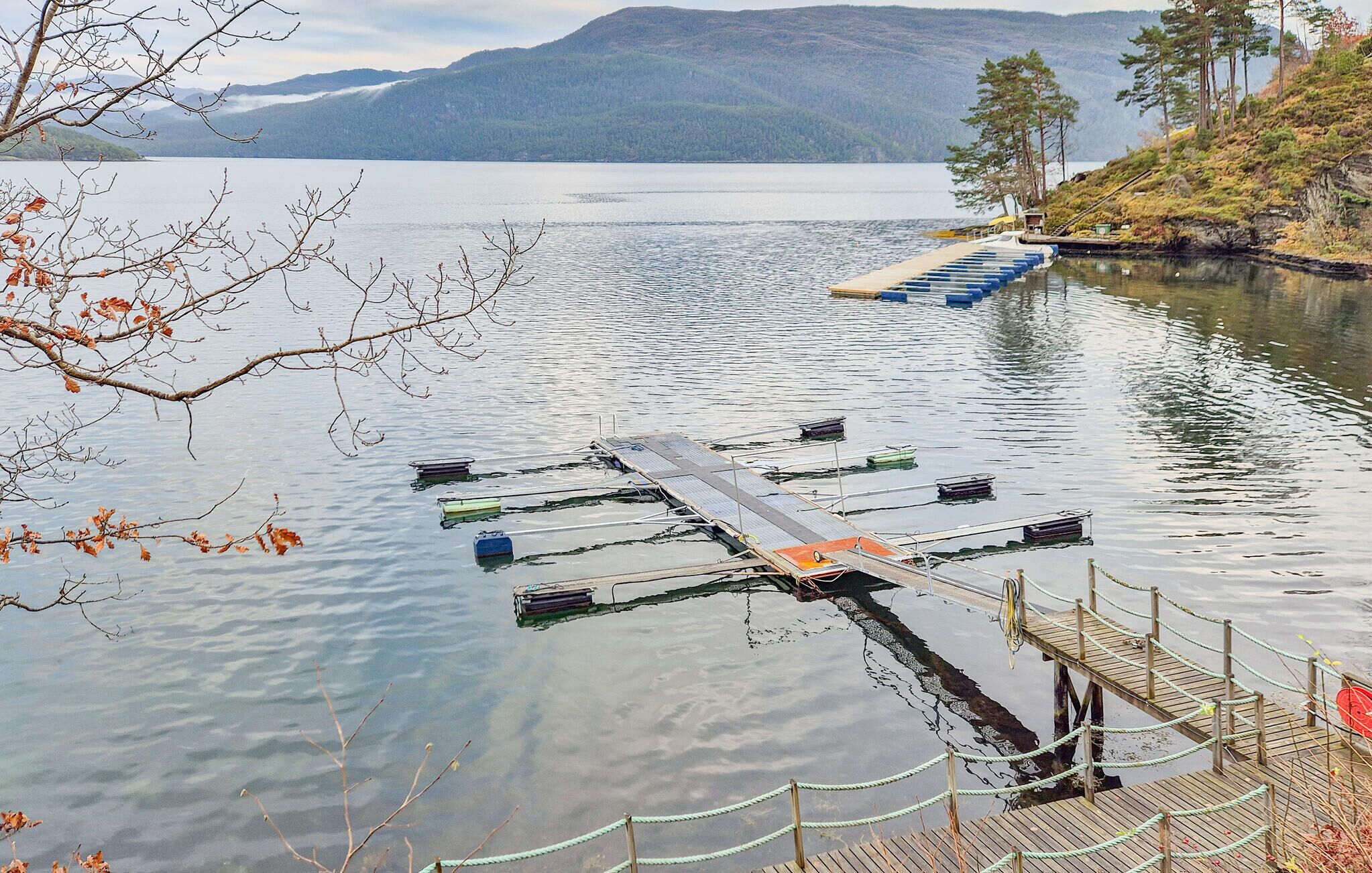 A dock extending into a calm lake with mountains in the background.