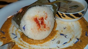 A plate with a food item wrapped in banana leaves, a bowl of soup, and a spoon. - Kodachadri Pathalagere Homestay (Hosanagara)