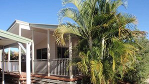 Una casa de dos pisos con un porche cubierto y una palmera en el patio delantero.