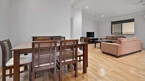 Un salón amplio con una mesa de comedor y sillas de madera, un sofá y un televisor.