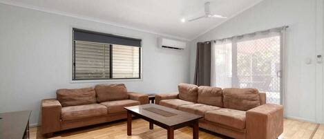 A living room with two sofas, a coffee table, and a ceiling fan.