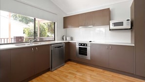 Una cocina moderna con electrodomésticos de acero inoxidable, armarios de madera y lavavajillas.