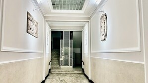 Un pasillo con suelo de mármol, paredes blancas y techo con diseño de cuadrícula.