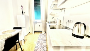 Cocina compacta con lavabo, hervidor y ventana con persianas.
