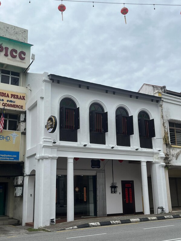 A white colonial-style building with three arched windows and a black door. - Hotel Ban Sheng Teik (Ipoh)