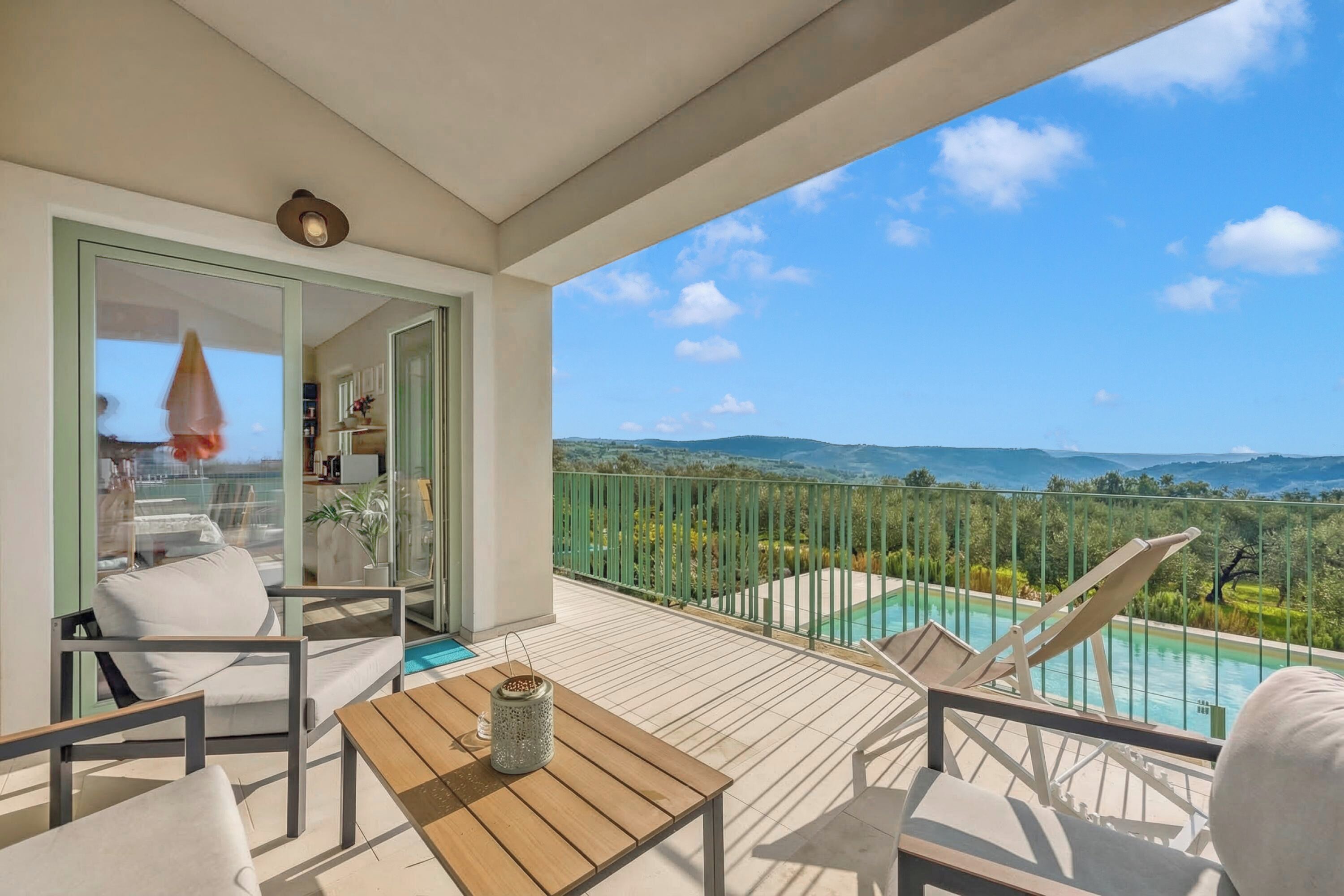 Ein Balkon mit Pool, Gartenmöbeln und Blick auf die Landschaft.