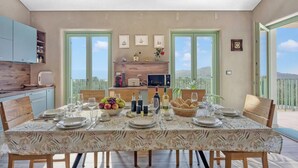 A dining area with a table set for four, kitchen cabinets, a window, and a balcony view.