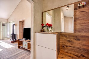 Een moderne woonkamer met een grote spiegel, houten vloeren, een televisie en een open haard.