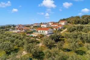 Un quartier résidentiel situé sur une colline, avec des maisons, une piscine et des oliviers.