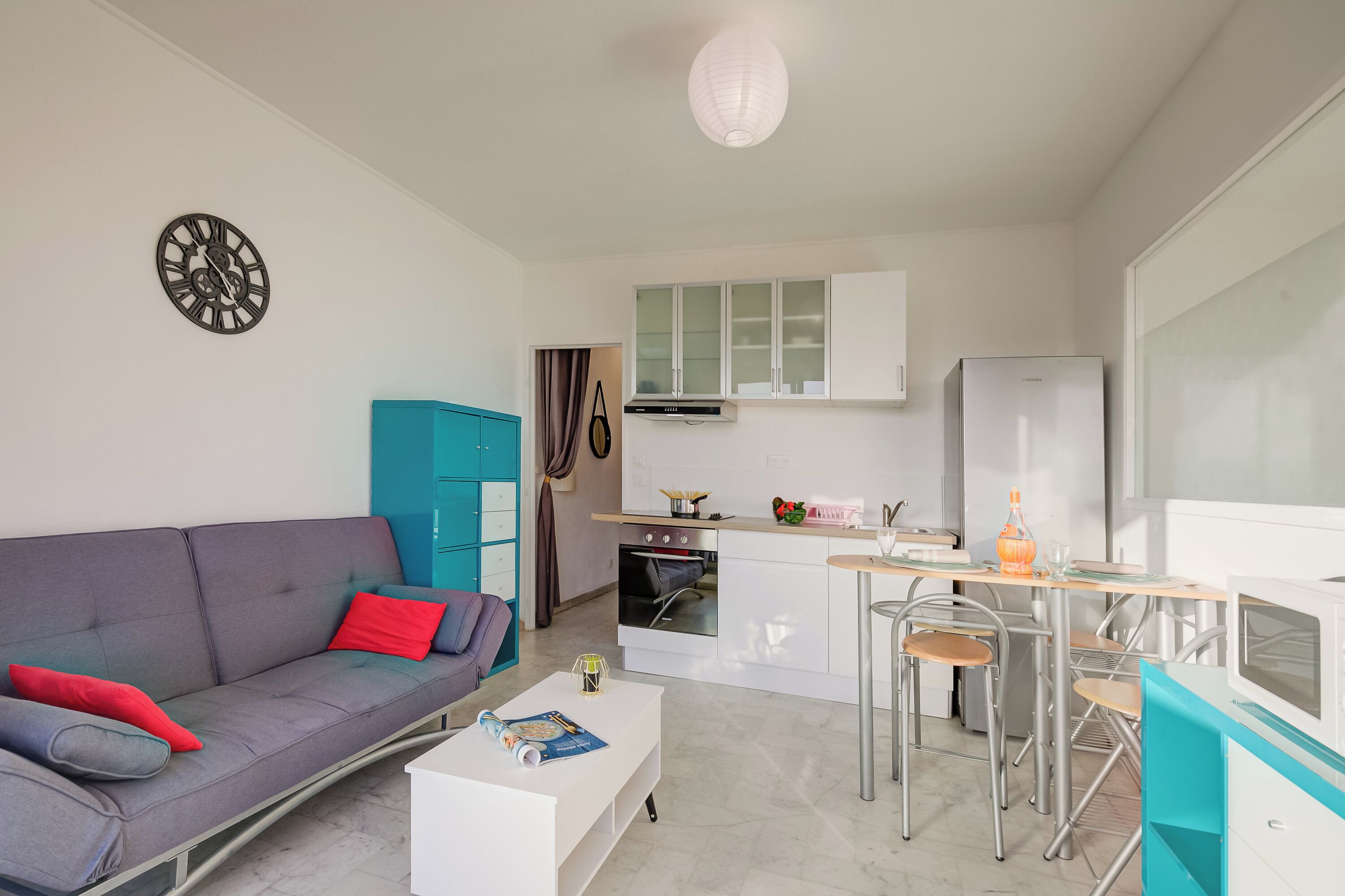 A compact living space with a sofa, a coffee table, a kitchenette, and a dining area.