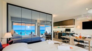 Une chambre d’hôtel avec un grand lit, un bureau, une chaise, une télévision et une vue sur l’océan.