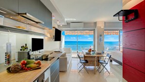 Une cuisine moderne dotée d’un grand îlot central, un coin repas offrant une vue agréable et une chambre avec un mur d’accent rouge.