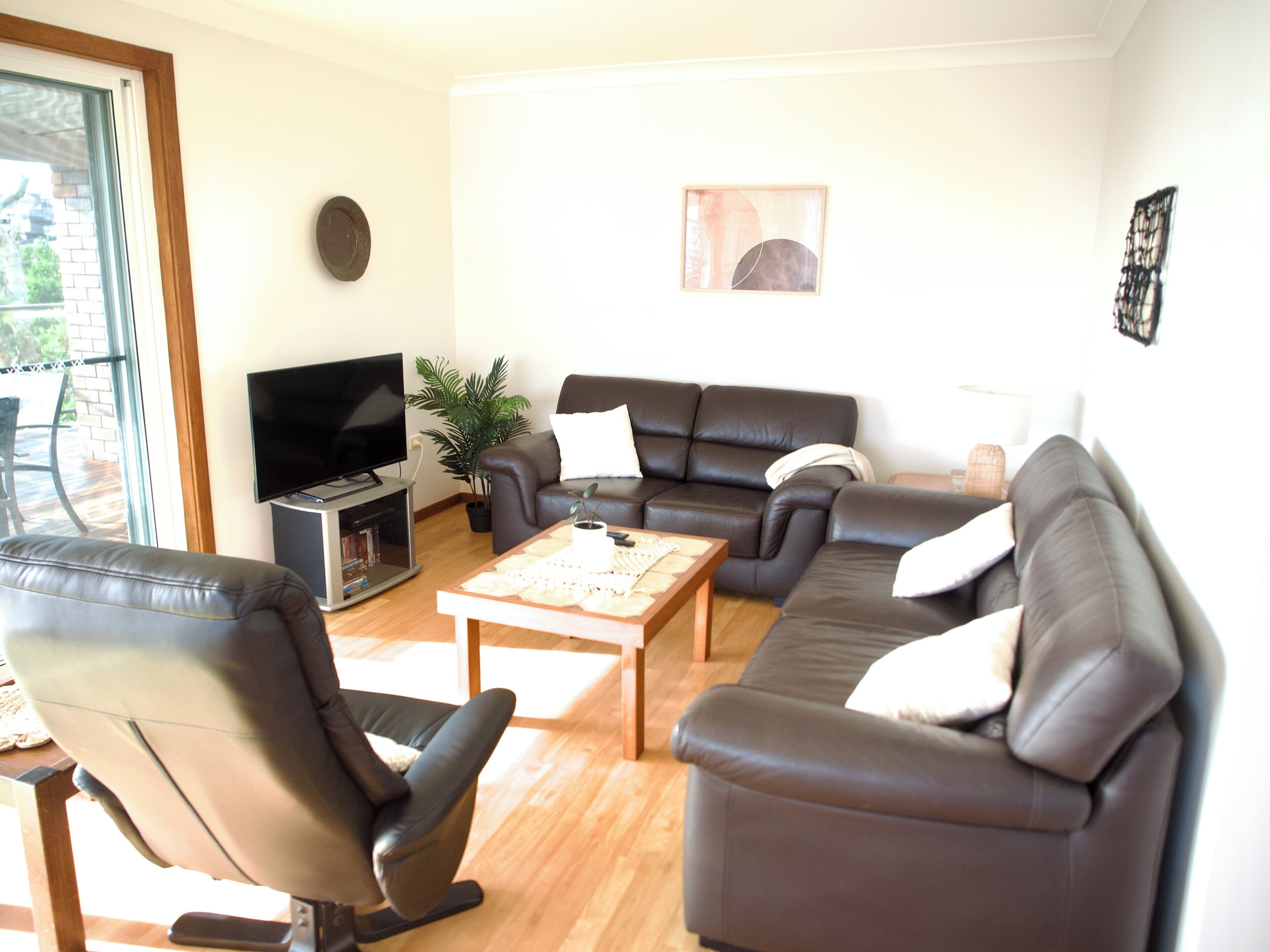 Ein Wohnzimmer mit einer Sofagarnitur, einem Couchtisch, einem Fernseher und einer Pflanze.