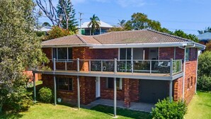 A two-story house with a balcony, brick exterior, and a well-maintained lawn.