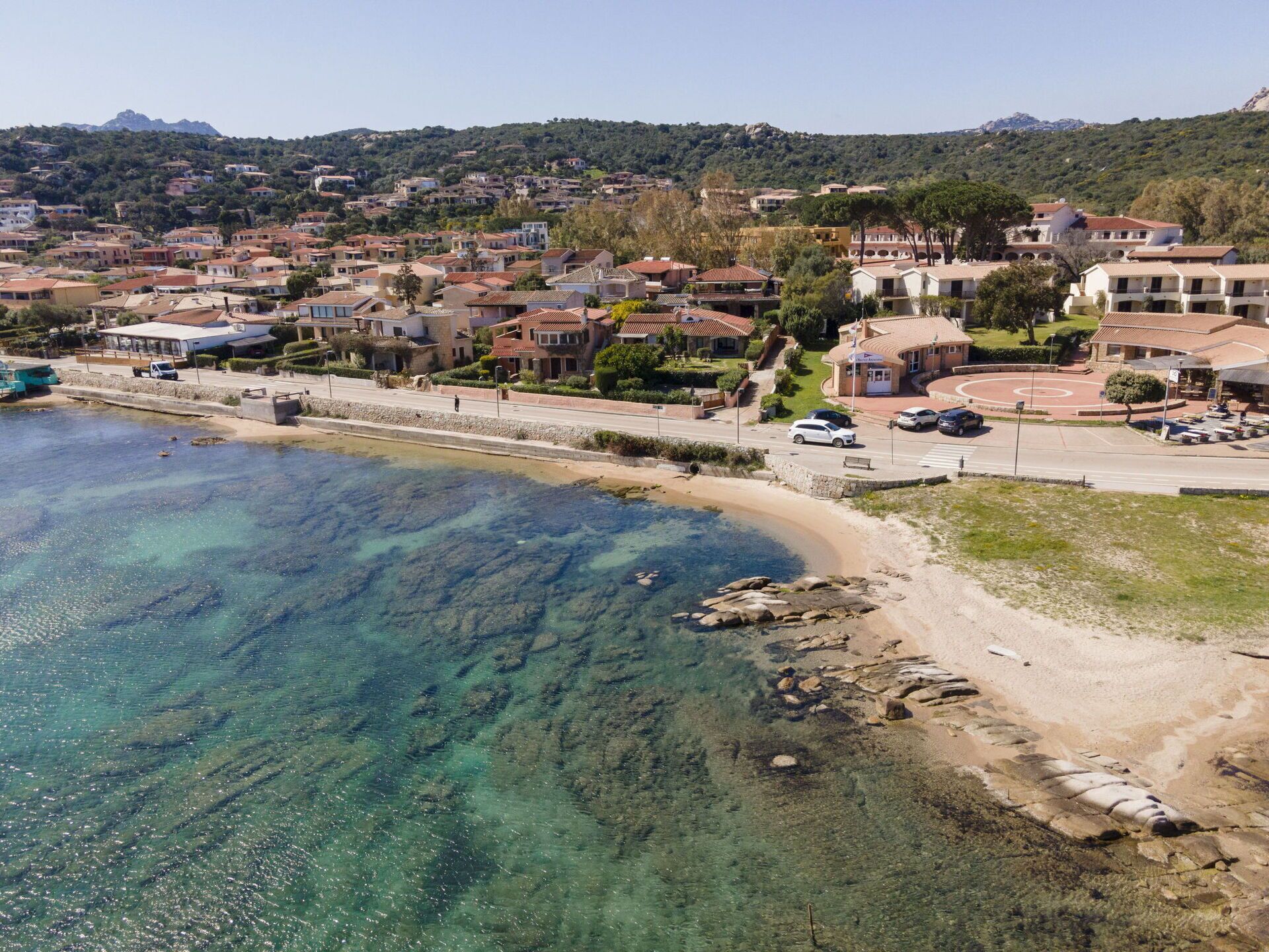 Eine Küstenstadt mit klarem, blauem Wasser, einem Sandstrand und Wohnhäusern.