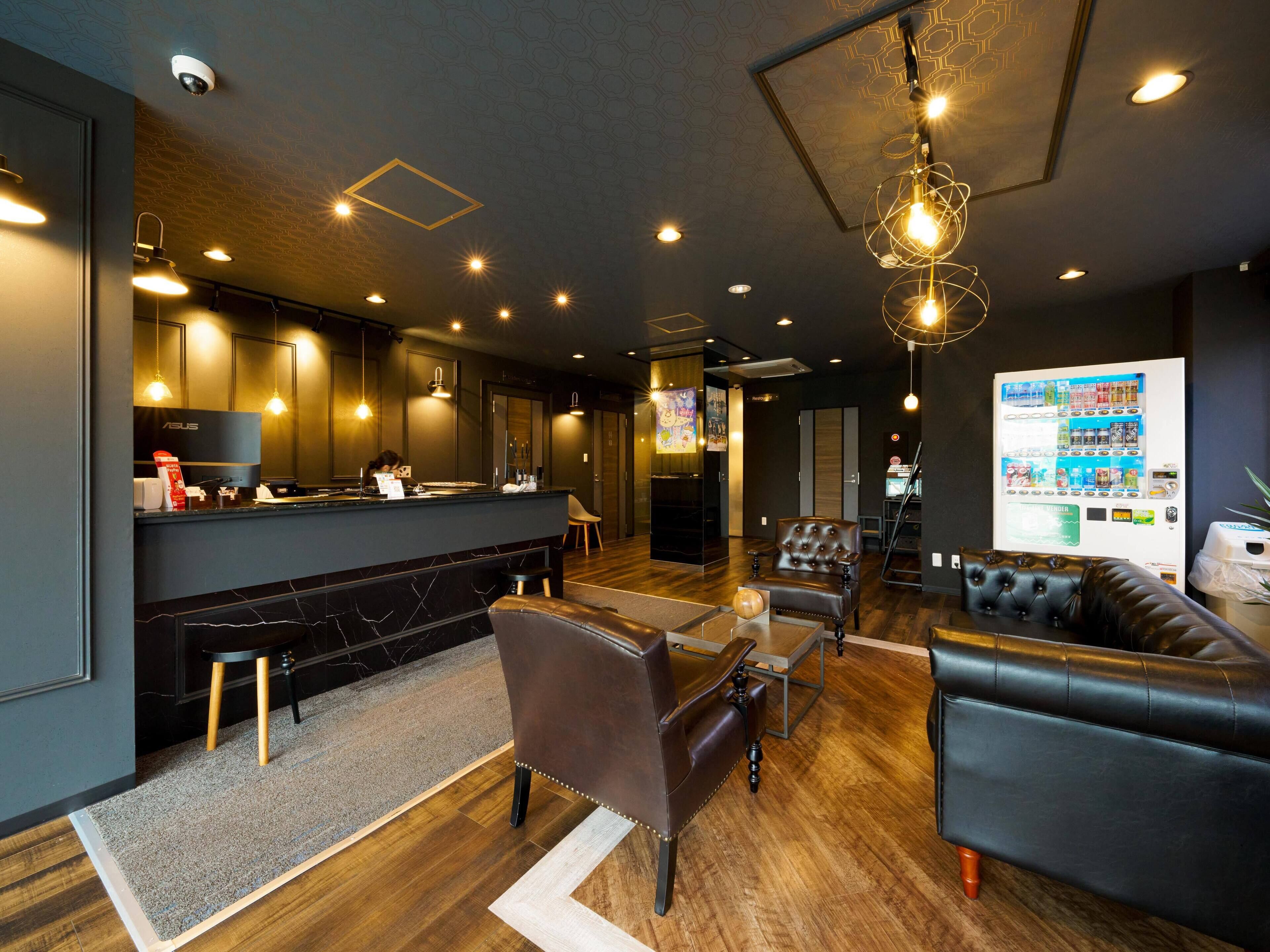 Un moderno vestíbulo de hotel con mostrador de recepción, zona de estar y máquina expendedora.