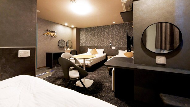 A modern hotel room with a large bed, a desk, and a chair. There are two bedside tables, a mirror, and a wall-mounted TV. - Hotel Areaone Naruto (Naruto)