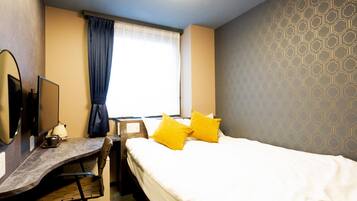 A hotel room with a bed, a desk, a chair, a TV, and a window with curtains.