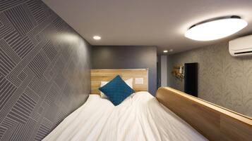 A modern hotel room with a bed, a headboard, a wall-mounted air conditioner, and a patterned wall.