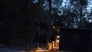 Una cabana amb un camí de grava que hi mena, envoltada d'arbres.