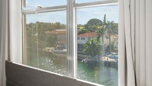 A hotel room with a large window offering a view of a marina and buildings. - Bay Harbor Sunset Apt 5C (Bay Harbor Islands)