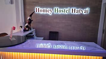 A reception desk with a sign reading 'Homey Hostel Hatyai' and a plush toy on the counter.