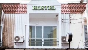 A hostel with a signboard, a large window, and a wooden door.