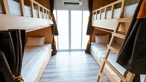 A room with bunk beds, a wooden floor, and an air conditioning unit.