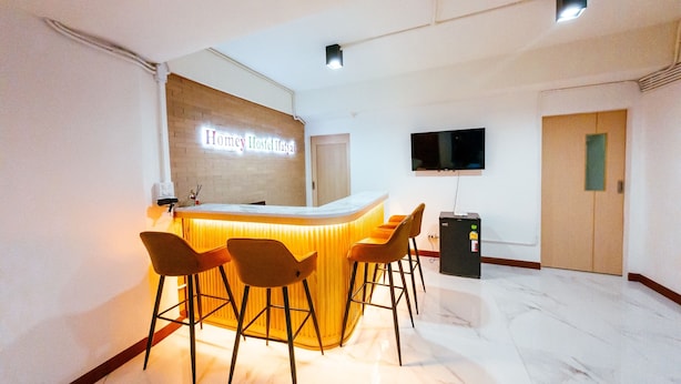 A reception area with a counter, bar stools, a TV mounted on the wall, and a door.