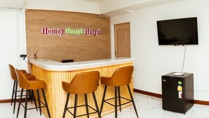 A hotel room with a reception desk, a TV, and a refrigerator.