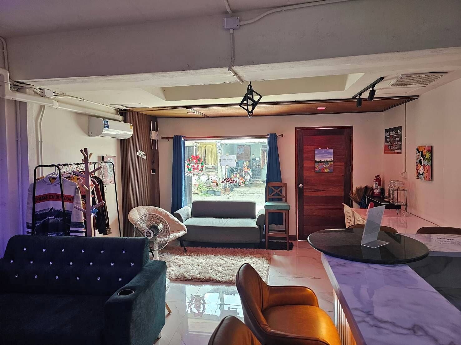 Una habitación con sofá, una silla, una mesa, un ventilador y vistas a la calle.