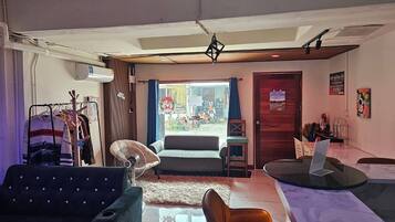 Una habitación con sofá, una silla, una mesa, un ventilador y vistas a la calle.