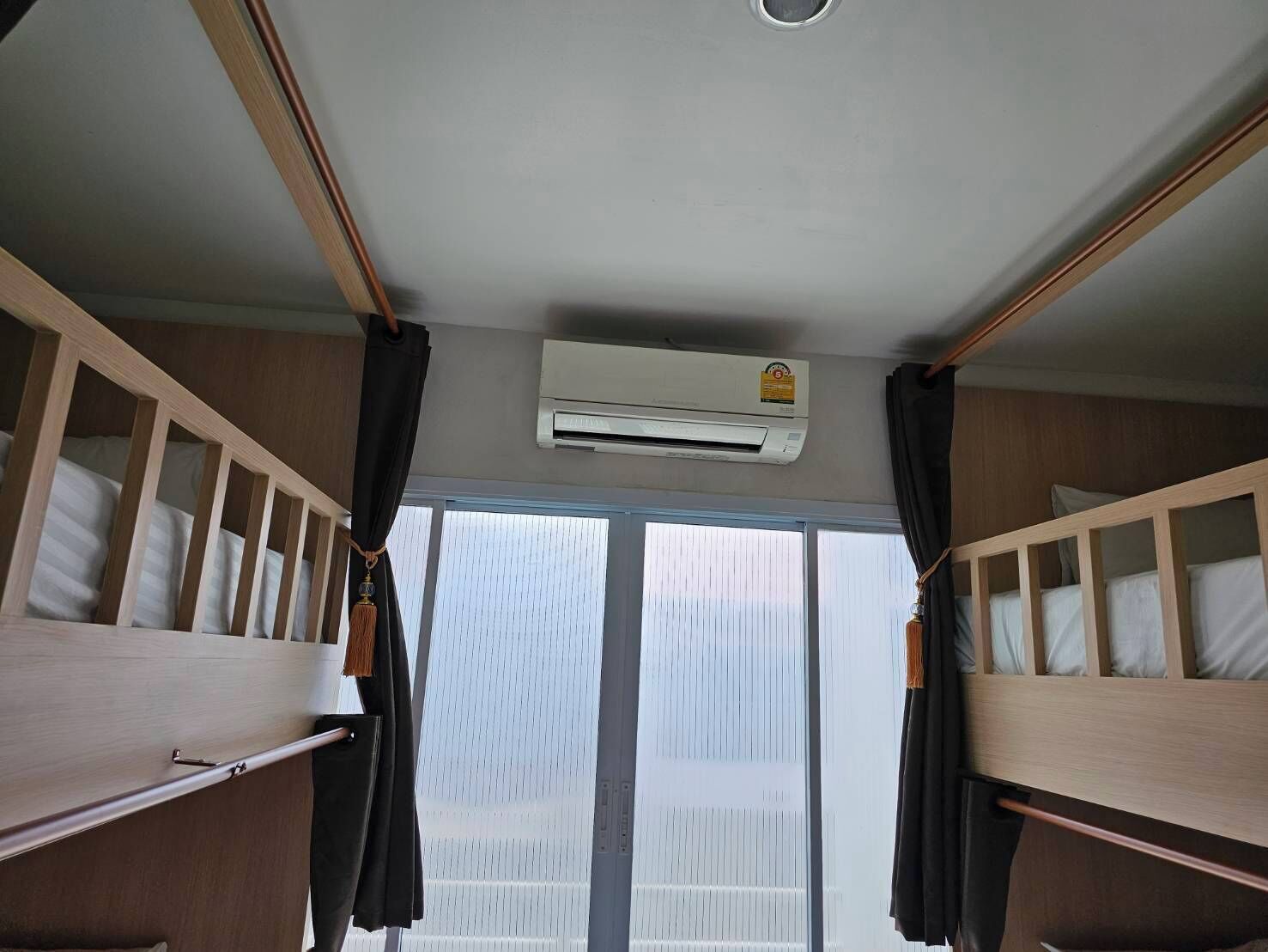 A room with bunk beds, an air conditioning unit, and a window with blinds.