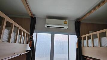 A room with bunk beds, an air conditioning unit, and a window with blinds.