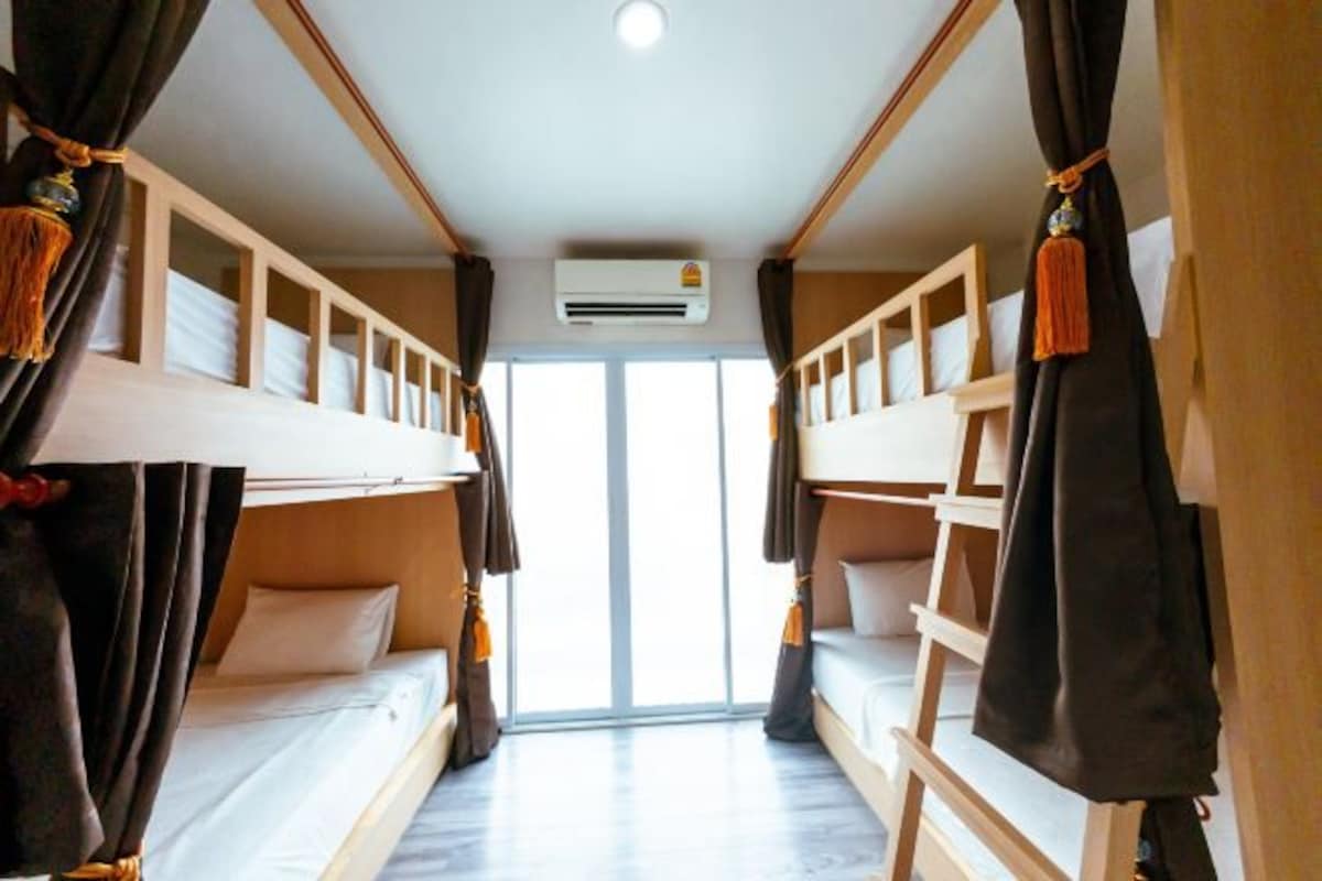 A room with bunk beds, a ceiling fan, and a window.