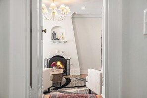 A modern living room with a fireplace, a chandelier, and a rug. - Dundee Gem, heated salt water pool, holiday décor (Omaha)