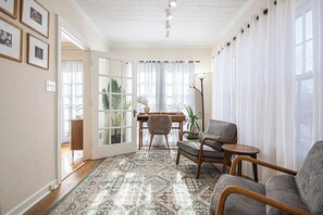 A spacious living area with a patterned rug, wooden furniture, and a view of a dining area through a glass door. - Dundee Gem, heated salt water pool, holiday décor (Omaha)