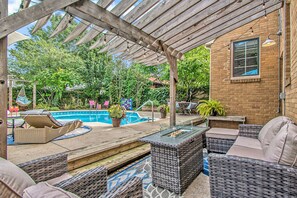 A covered patio area with wicker furniture, a pool, and potted plants. - Dundee Gem, heated salt water pool, holiday décor (Omaha)