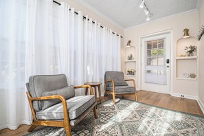 A room with two wooden-framed chairs, a patterned rug, a white door with a window, and a shelf with decorative items. - Dundee Gem, heated salt water pool, holiday décor (Omaha)