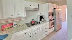 Een moderne keuken met witte kastjes, roestvrijstalen apparatuur en een granieten werkblad.