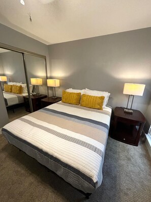 Relax in a spacious room with a large bed, two bedside tables, and a large mirror.