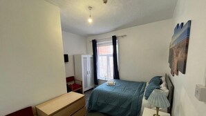 A bedroom with a bed, a dresser, a nightstand, a window with curtains, and a ceiling fan. - Ensuite Double Room 5mins to the sea (Blackpool)