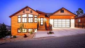 A modern two-story house with a garage, wooden siding, and a well-maintained front yard.