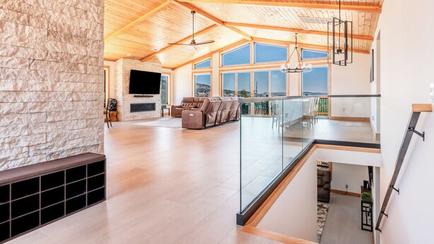 A spacious living area with a stone wall, a fireplace, and a large TV. There is a balcony with a view of the outdoors.