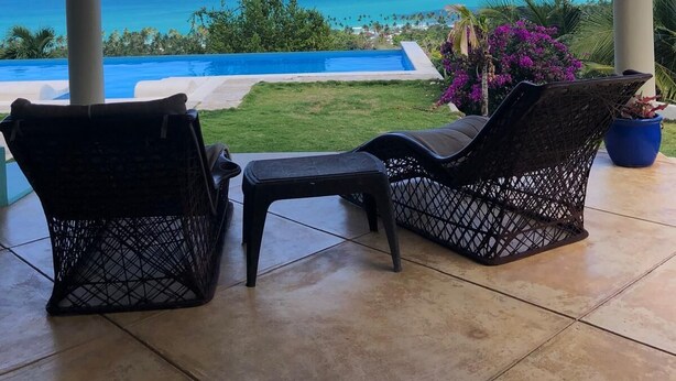 A covered patio with two wicker chairs, a hanging lantern, and a view of the ocean and a swimming pool. - Bella Vista, Las Terrenas (Las Terrenas)