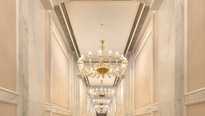 Un pasillo largo y elegante con paredes de mármol y un candelabro central.