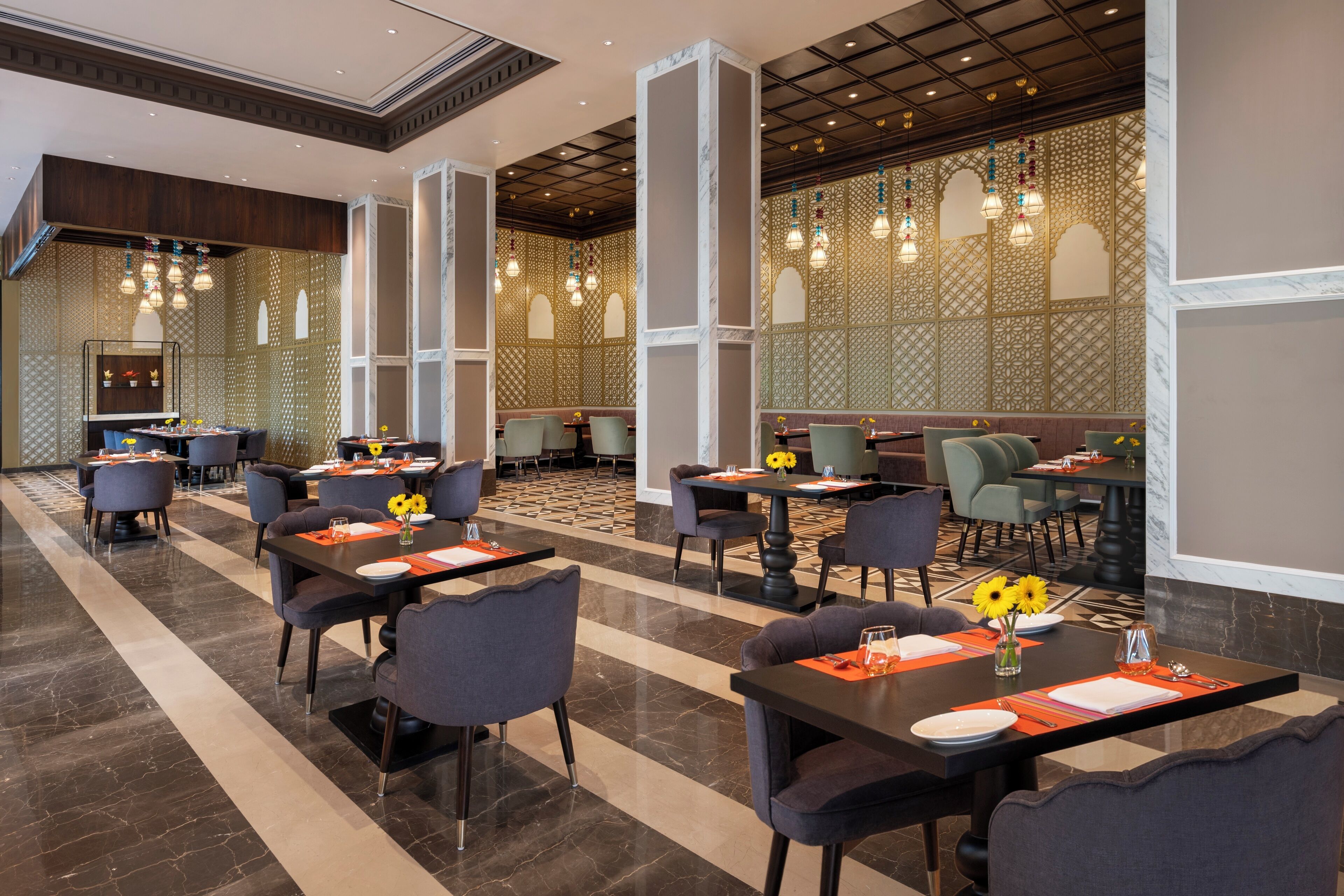 A spacious hotel lobby with multiple dining areas, each featuring tables and chairs.