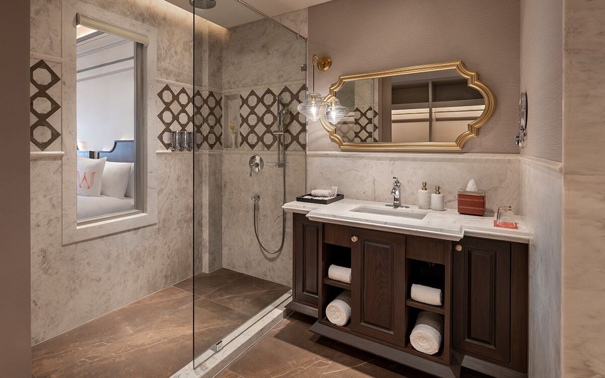 A modern bathroom with a glass shower enclosure, a large mirror, and a vanity with dark wood cabinets.